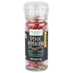 Organic pink peppercorns in a glass bottle with grinder top, showcasing their vibrant color and texture.