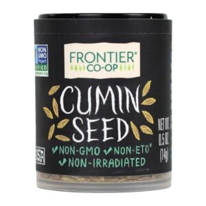 Whole cumin seeds in a glass jar with a rustic label.