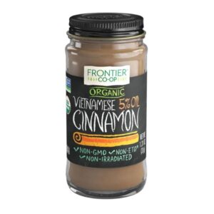 Frontier® Organic Ground Vietnamese Cinnamon in a glass jar with a metal cap, showcasing its rich brown color and texture.
